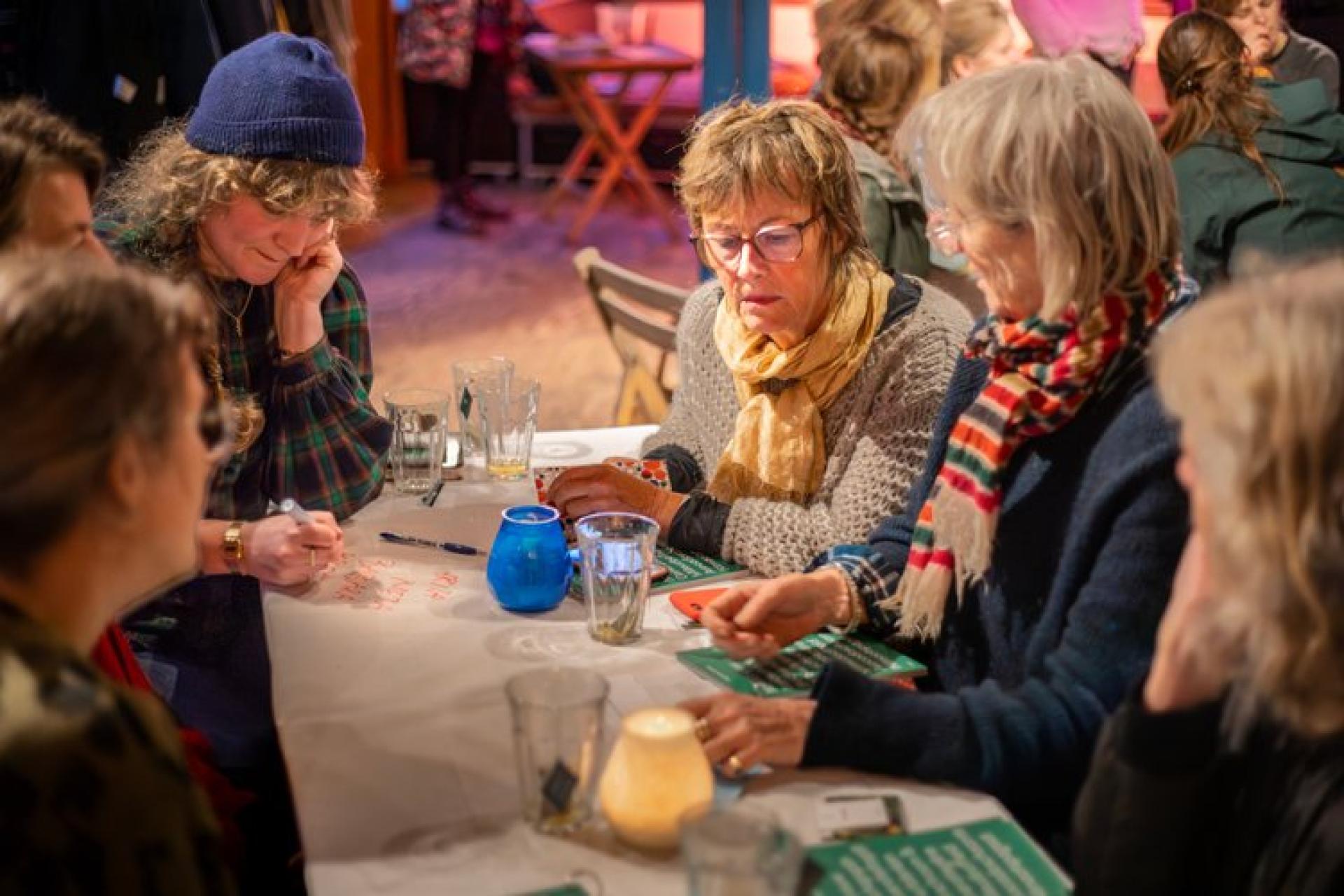 vijf vrouwen zitten aan een tafel